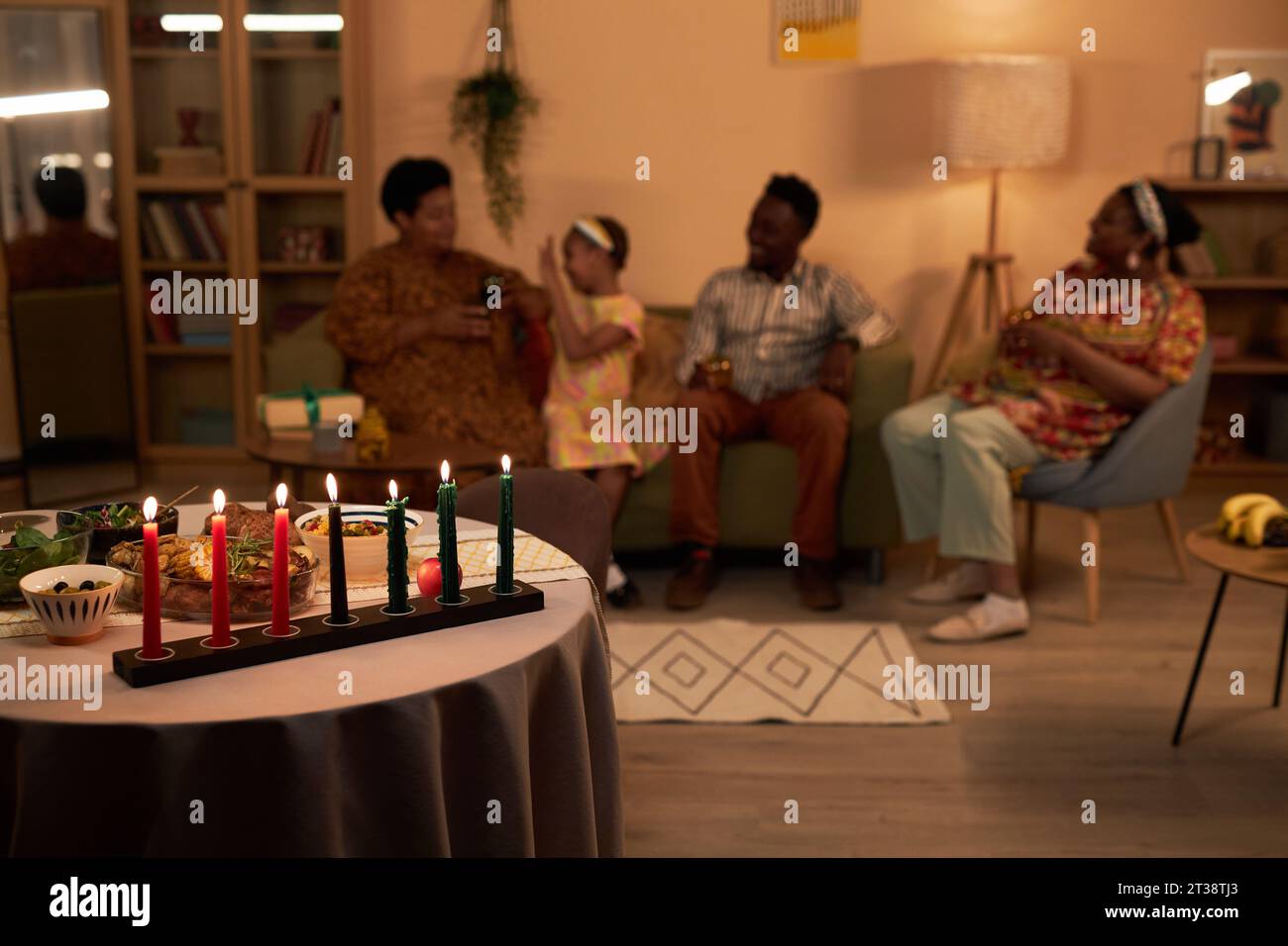 Tavolo da pranzo decorato per vacanze kwanzaa e famiglia che parla in sottofondo Foto Stock