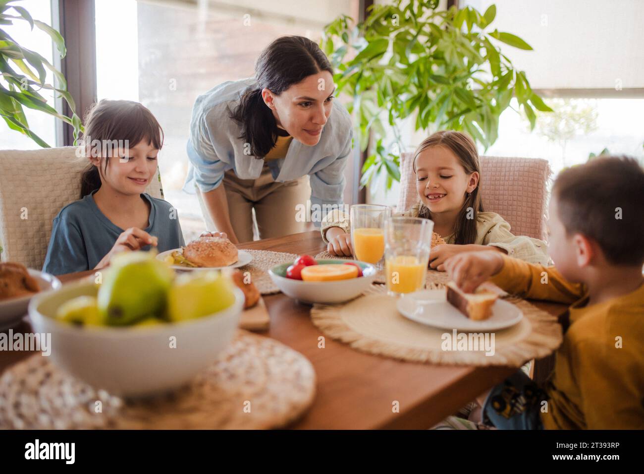 La madre prepara la colazione per i bambini, al mattino. Amore materno e cura per la famiglia e la famiglia. Foto Stock