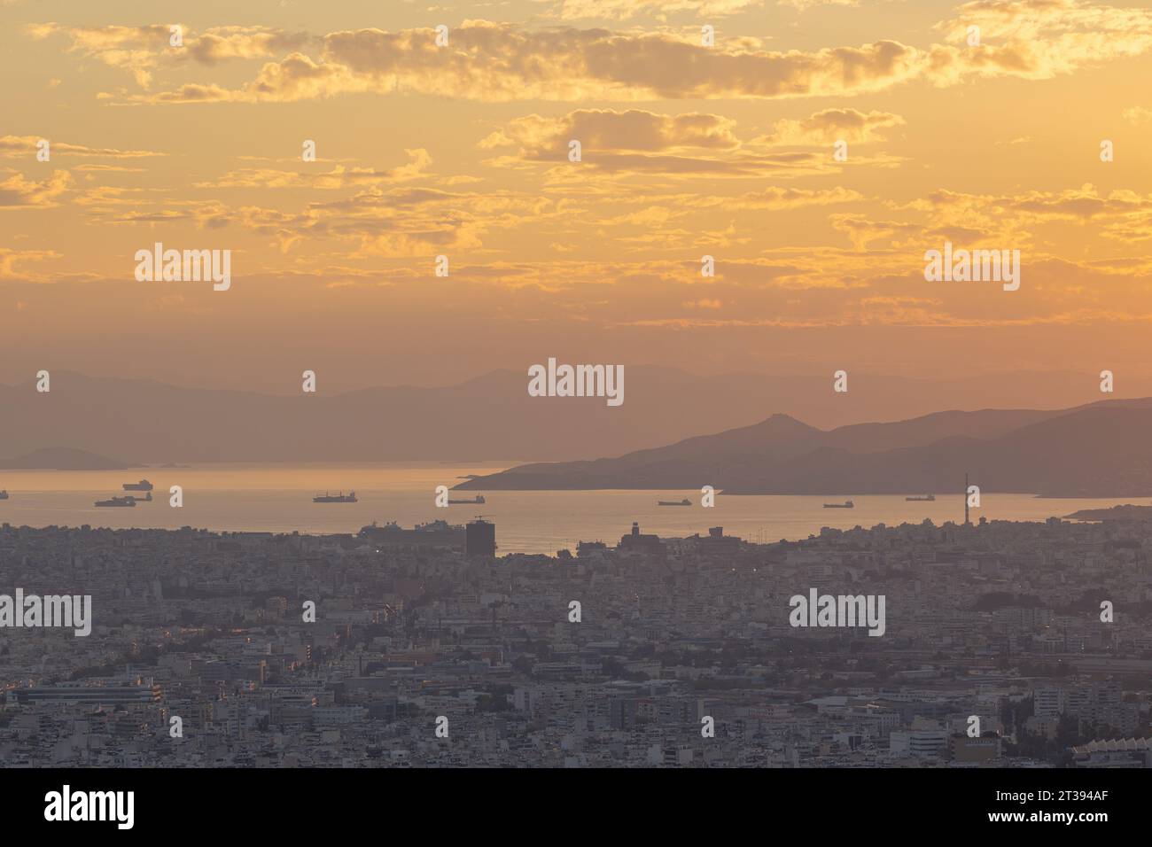 Una vista al tramonto di Atene, presa dal Monte Lycabettus verso il porto e i moli Foto Stock