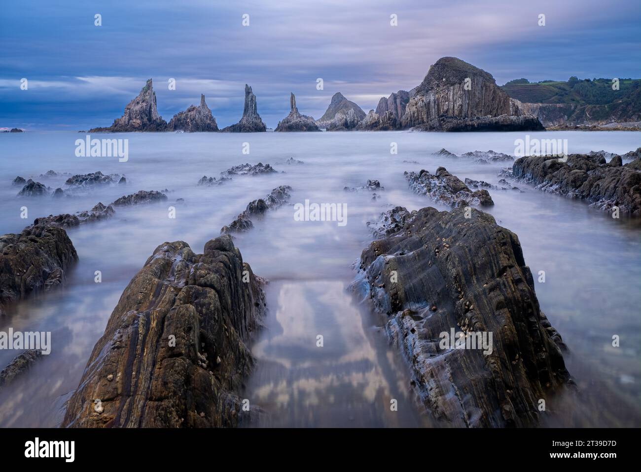 Lunga esposizione di onde che si lavano su rocce e scogliere contro il cielo nuvoloso nelle Asturie, in Spagna Foto Stock