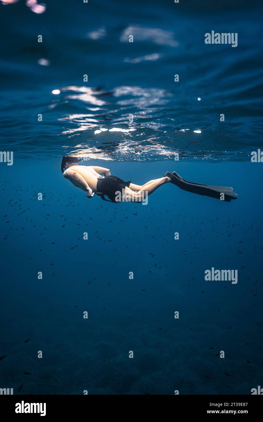 Foto di una scena subacquea di un uomo che indossa una maschera da snorkeling che nuota nelle acque cristalline di Minorca Foto Stock