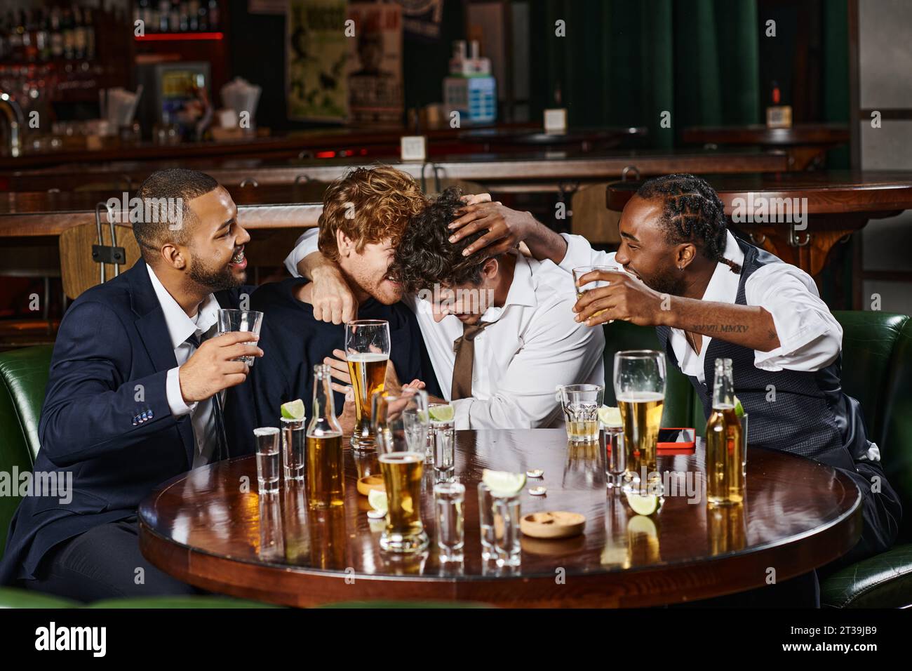 amici maschi multietnici che si abbracciano durante la festa di addio al celibato al bar, tequila, whisky e birra Foto Stock