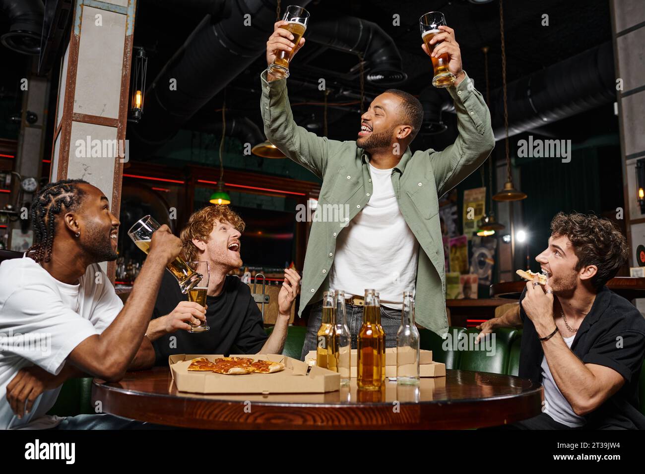 allegro afroamericano che prepara due bicchieri di birra vicino agli amici durante la festa di addio al celibato al bar Foto Stock