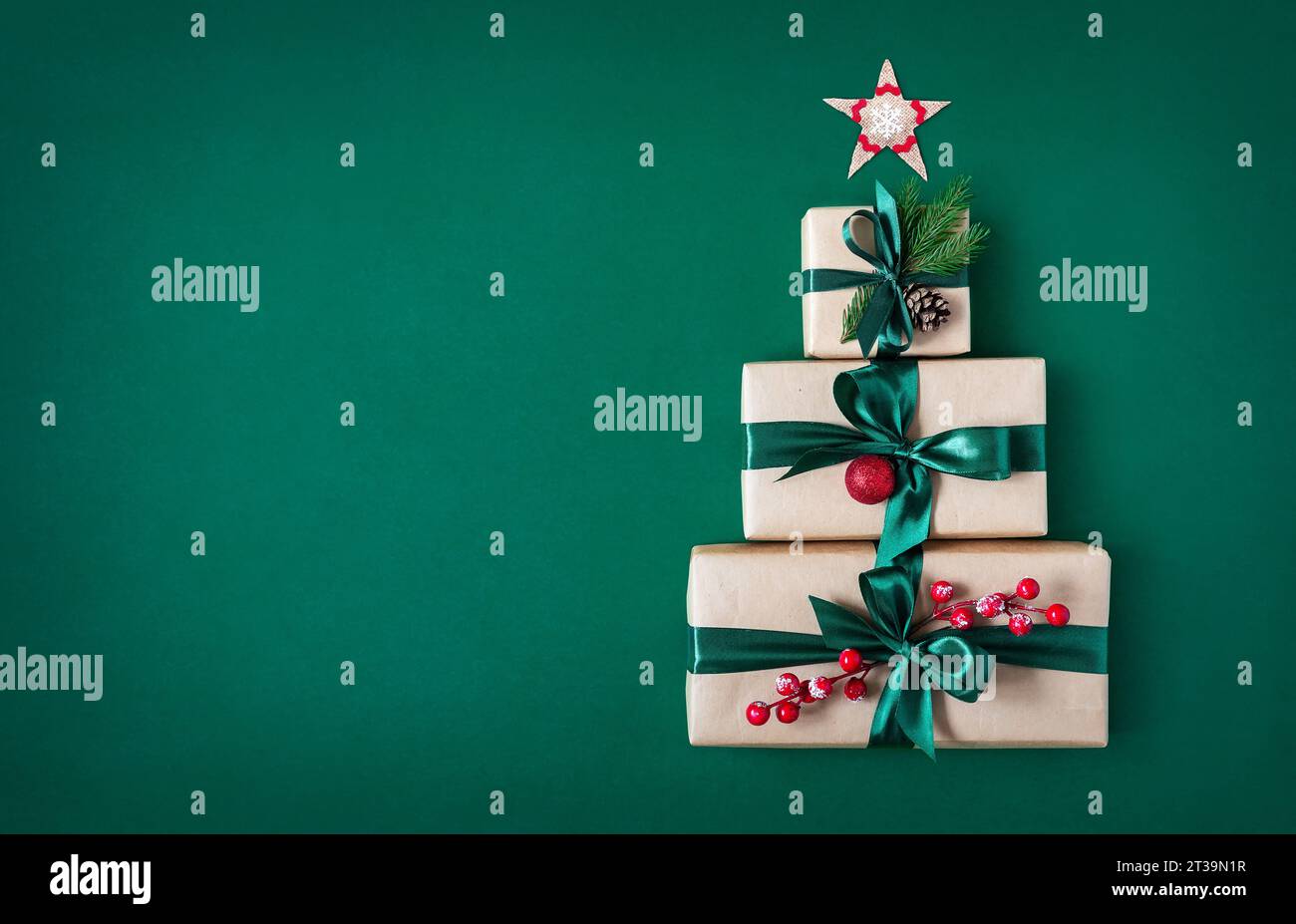 Tre confezioni regalo su sfondo verde a forma di albero di Natale e stella del Natale. Sfondo festivo. Foto Stock