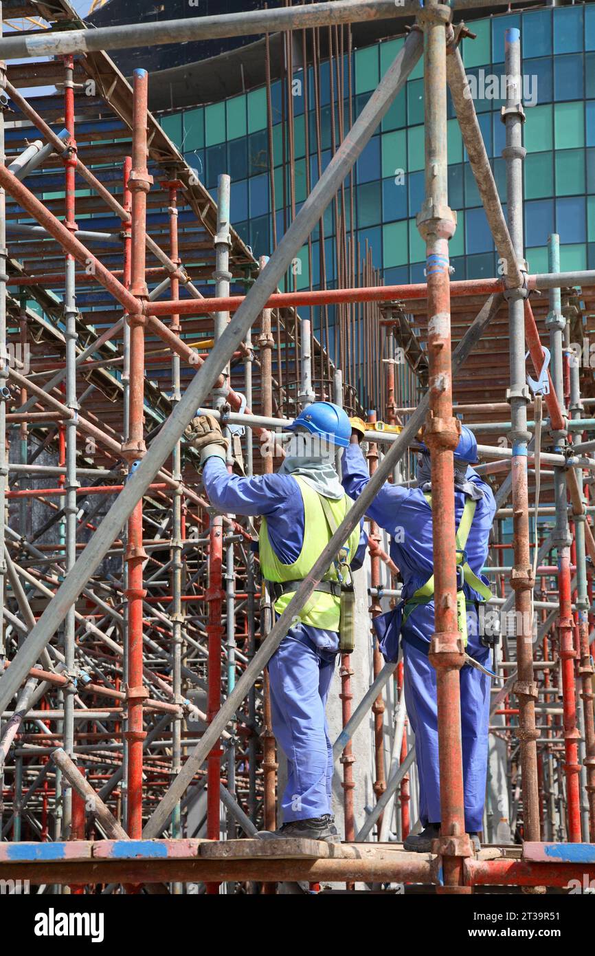 I lavoratori stranieri provenienti da India e Pakistan assemblano impalcature in un grande cantiere edile ad Abu Dhabi, negli Emirati Arabi Uniti. Foto Stock