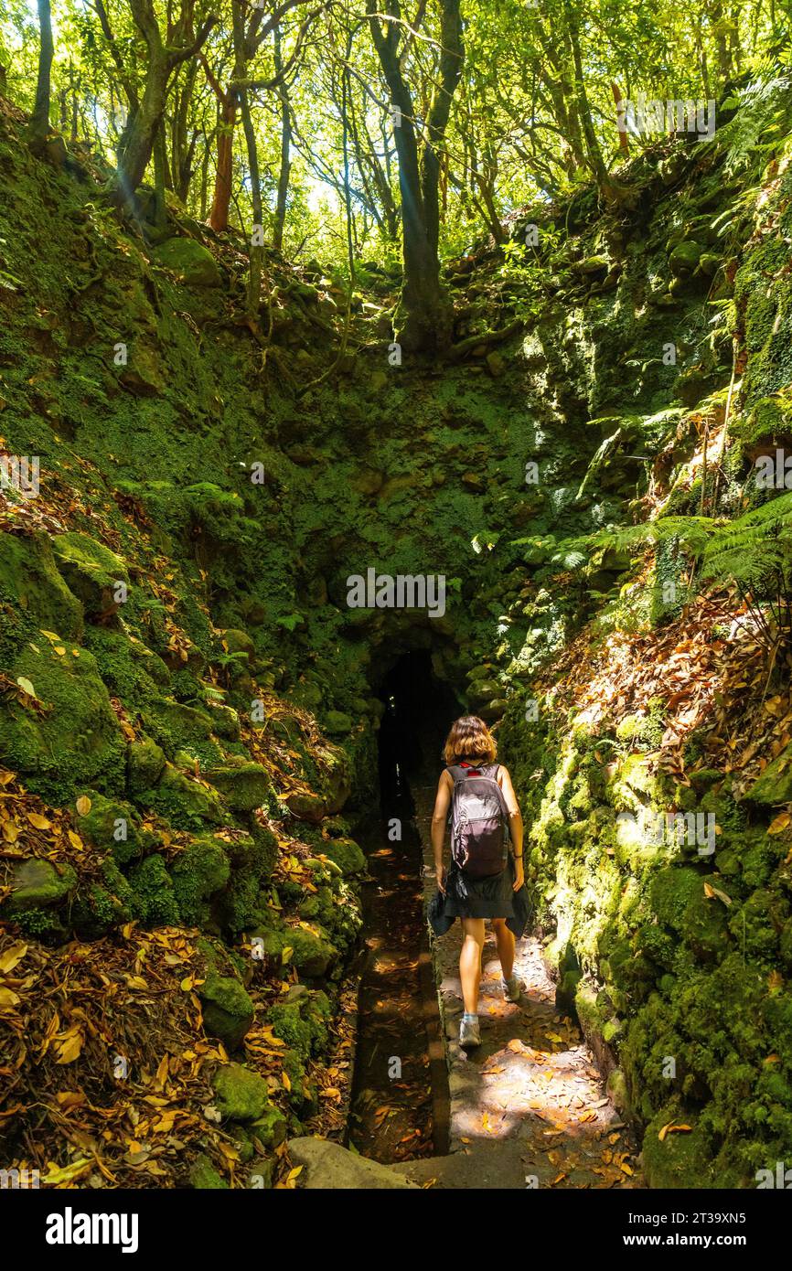 Eine junge Frau auf dem Weg zu einer Höhle auf dem Wanderweg in Levada do Caldeirao Verde, Queimadas, Madeira Foto Stock