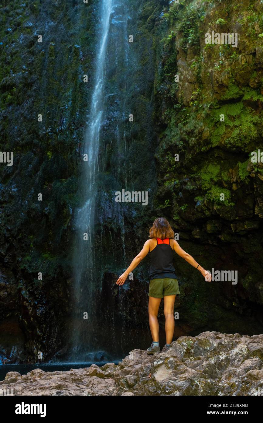 Eine junge Frau am beeindruckenden Wasserfall an der Levada do Caldeirao Verde, Queimadas, Madeira Foto Stock