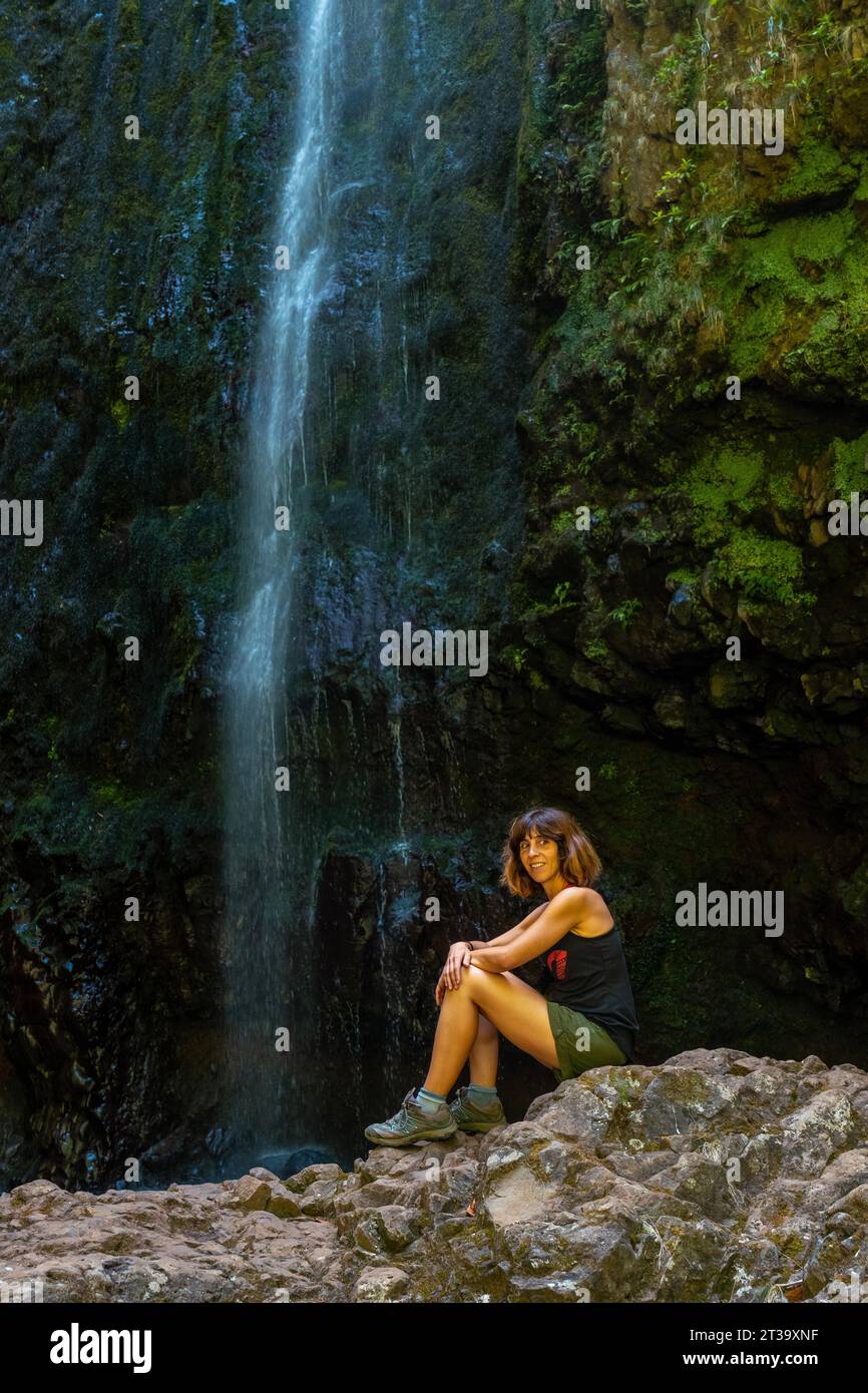 Eine junge Frau am Wasserfall am Ende des Wasserfallweges a Levada do Caldeirao Verde, Queimadas, Madeira Foto Stock