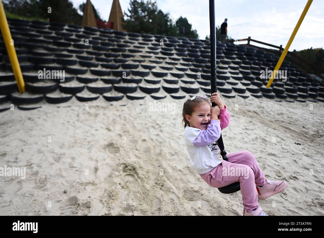 Simpatica bambina che gioca su un altalena nel parco giochi all'aperto. Foto Stock