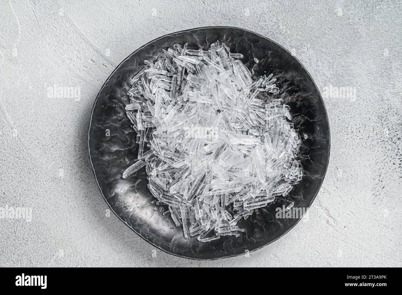 Cristalli di mentolo in una piccola piastra in acciaio. Sfondo bianco. Vista dall'alto. Copia spazio. Foto Stock