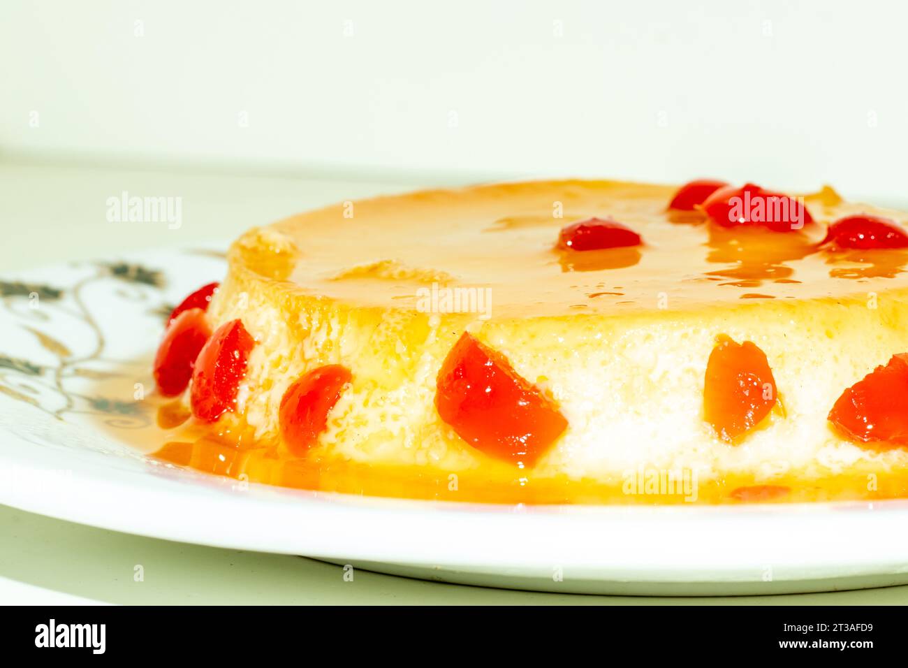 Il budino fatto in casa viene servito condito con frutti di ciliegia rossi. Un budino è un alimento dolce cotto a base di ingredienti come latte, zucchero, farina e uova Foto Stock