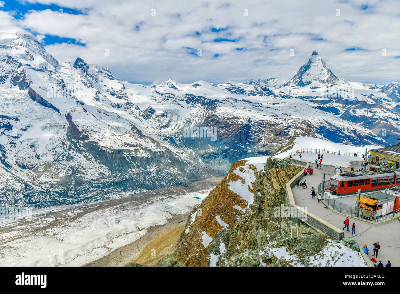Treno rosso sulla ferrovia innevata alla stazione di cima con i turisti e la cima del Cervino e il ghiacciaio Gorner in Svizzera Foto Stock