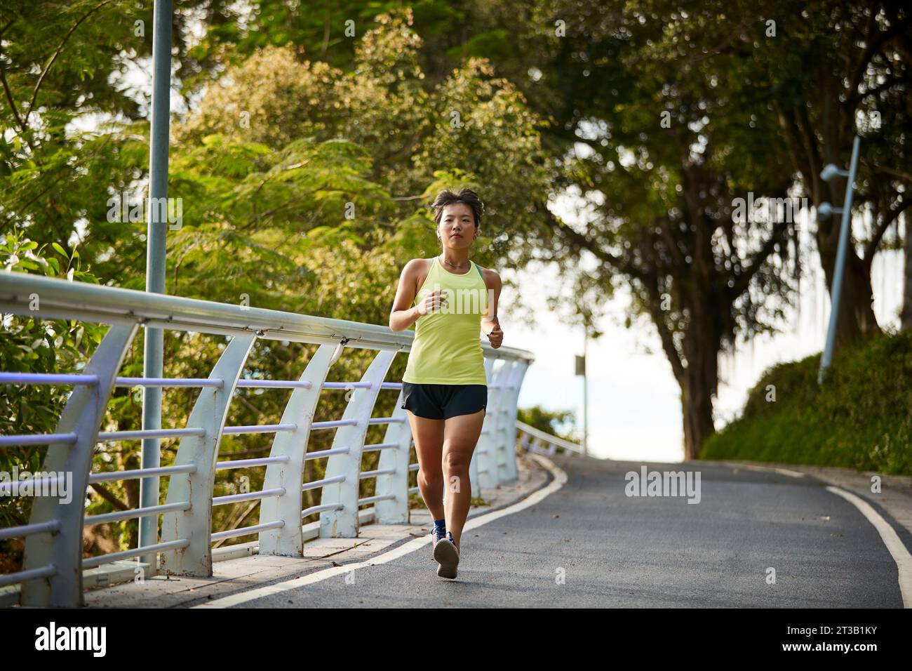 giovane donna asiatica che corre jogging esercitandosi all'aperto nel parco cittadino Foto Stock