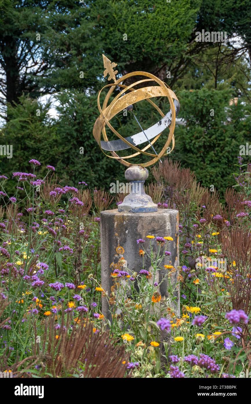 Meridiana a sfera armillare in un giardino circondato da fiori selvatici Foto Stock