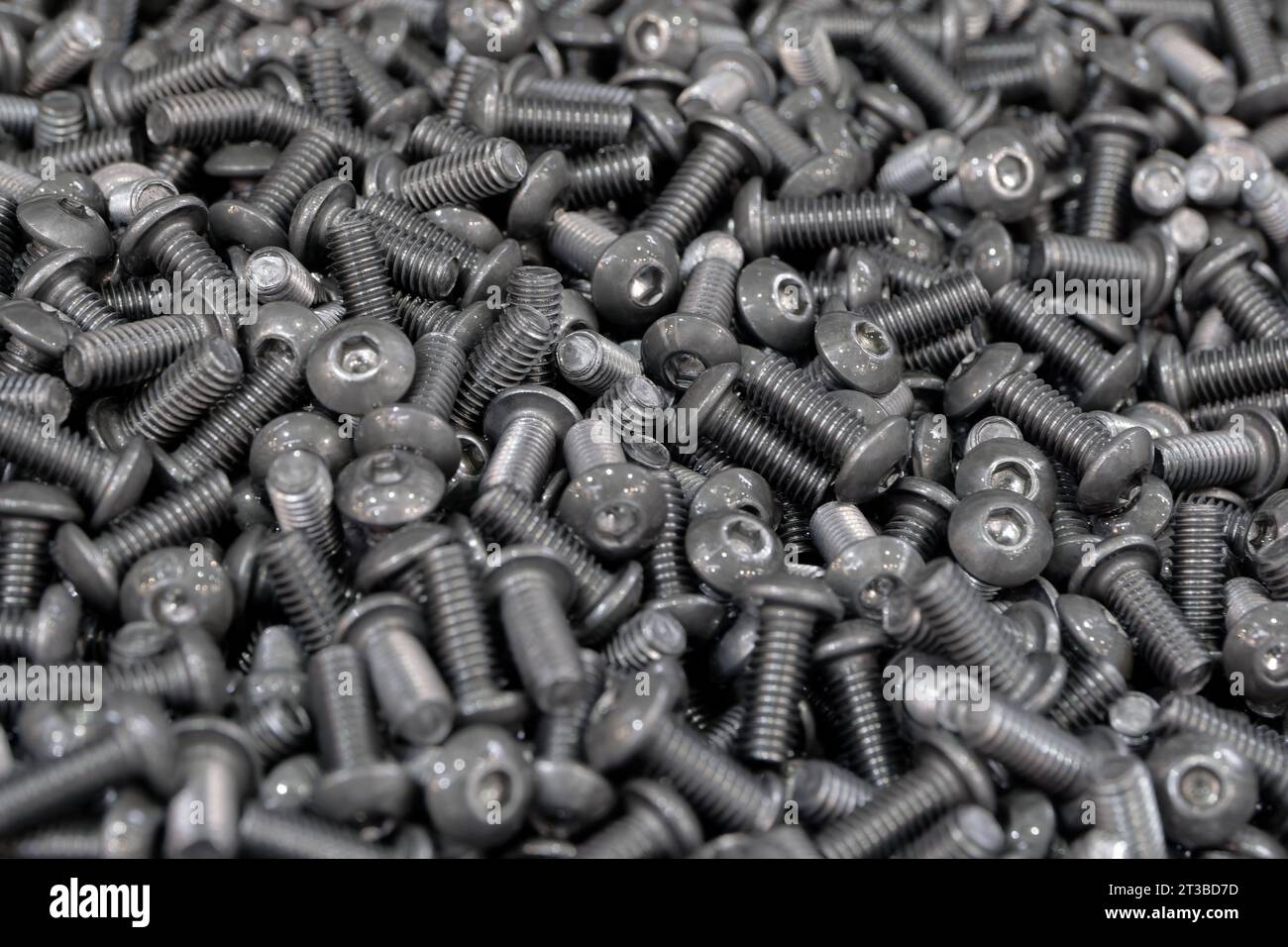 Gruppo molto ampio di bulloni a vite in acciaio nero, sfondo industriale astratto Foto Stock