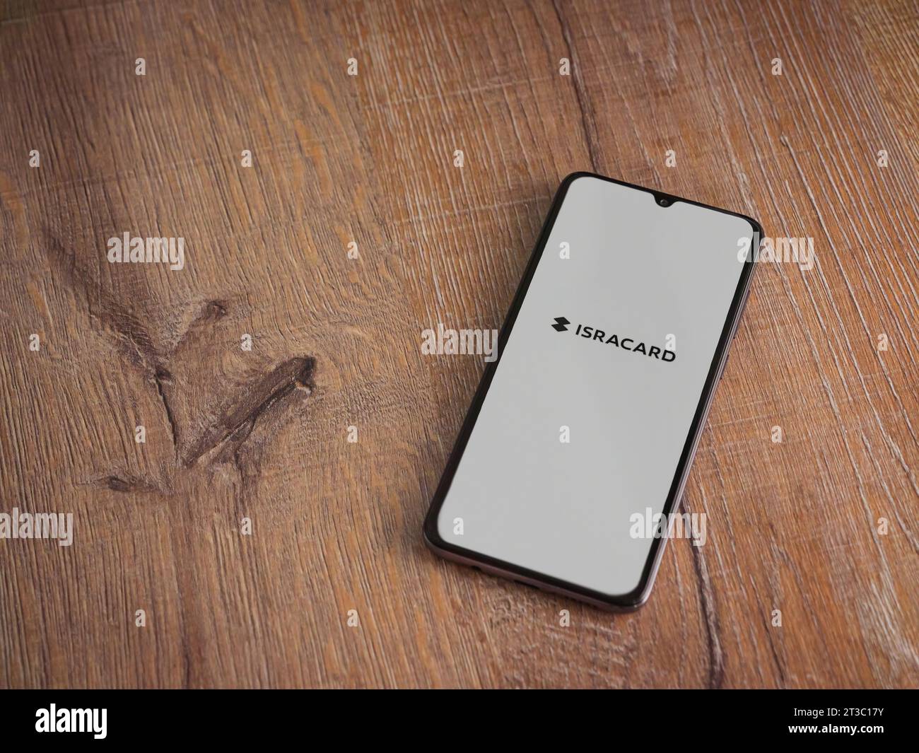 LOD, Israele - 16 luglio 2023: Schermata di lancio dell'app Isracard su smartphone su sfondo ligneo. Vista dall'alto con spazio per la copia. Foto Stock
