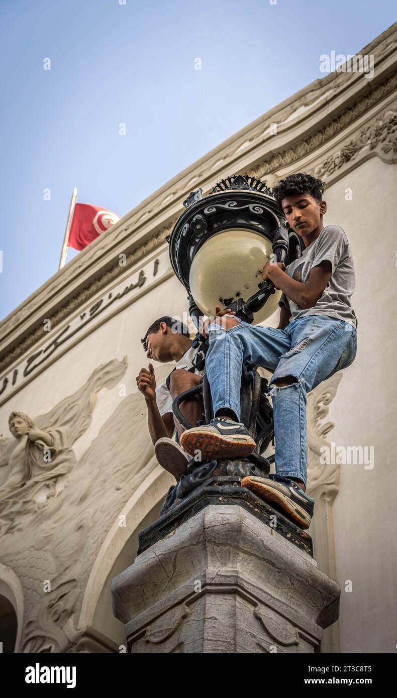 I ragazzi al semaforo (con la bandiera tunisina sullo sfondo) durante il raduno pro-Palestina a Tunisi in centro dopo l'esplosione dell'ospedale a Gaza Foto Stock