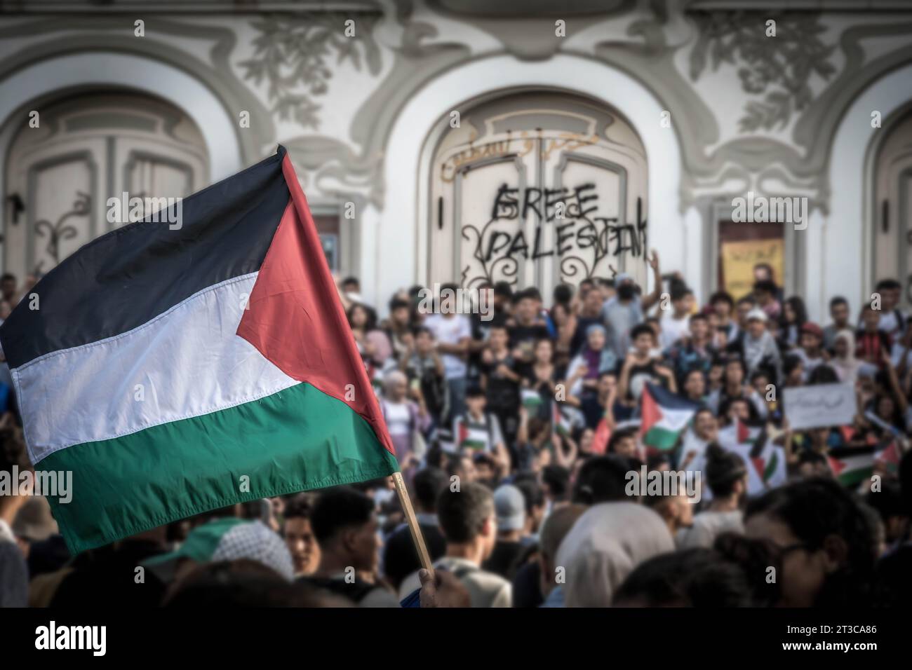 La bandiera palestinese alla manifestazione di protesta pro-palestinese a Tunisi con la folla di manifestanti e le parole "Palestina libera” sul muro Foto Stock