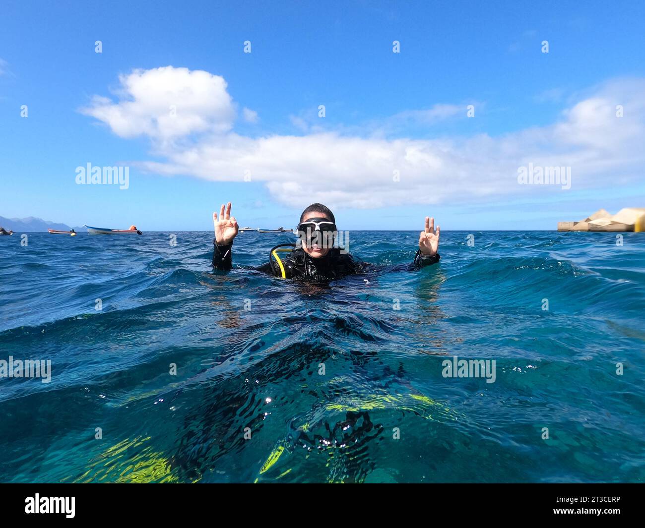 Donna subacquea che galleggia sulla superficie dell'acqua e fa il cartello "OK" con entrambe le mani per segnalare che tutto è corretto. Controllo di sicurezza, comune Foto Stock