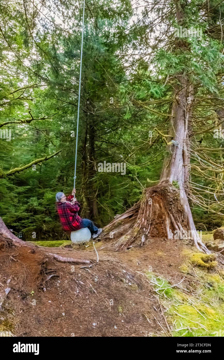 Karen Rentz su un'altalena fatta di detriti sulla spiaggia presso la vecchia Rose Harbour Whaling Station, nel Gwaii Haanas National Park Reserve, Haida Gwaii, British col Foto Stock