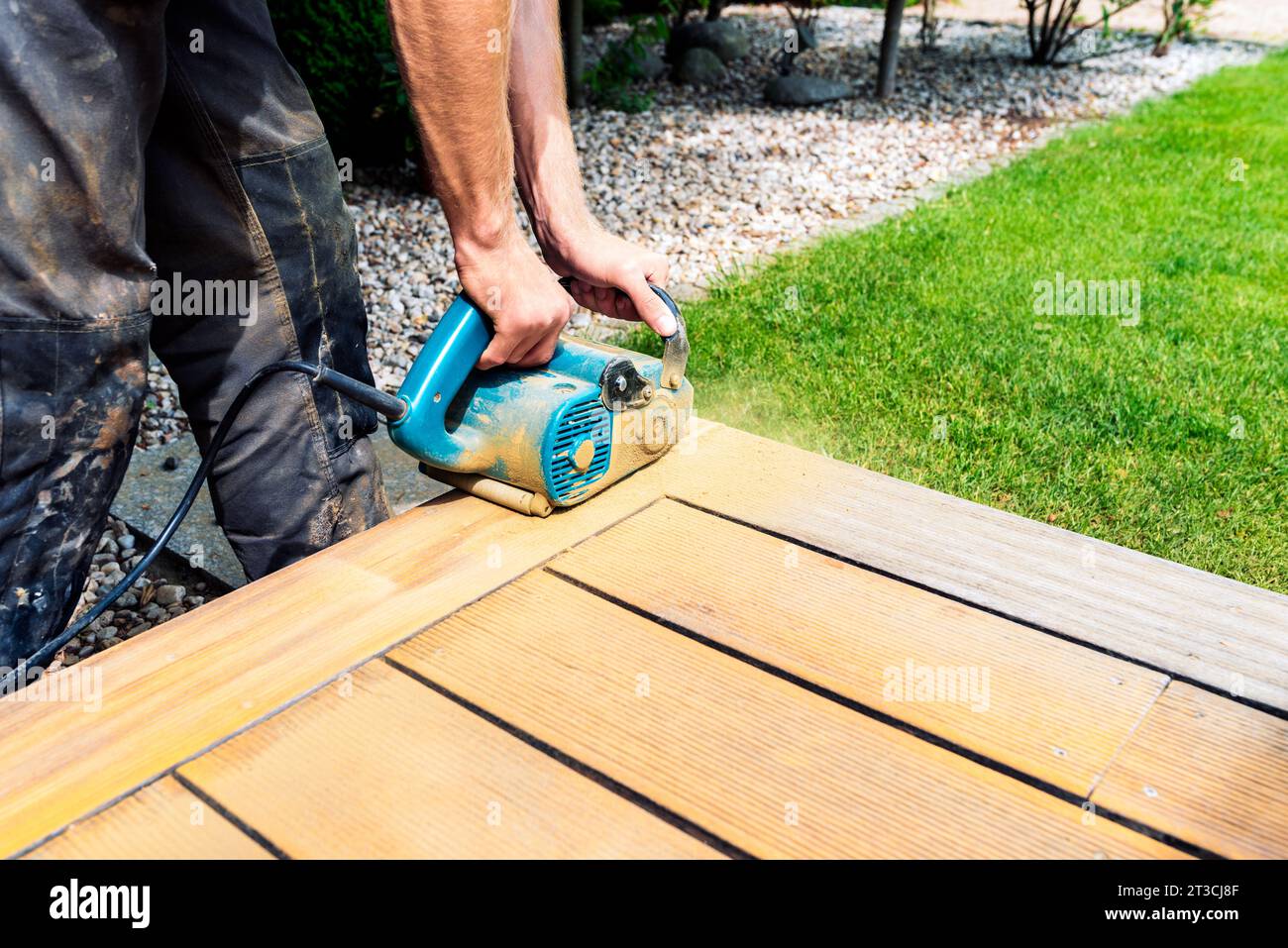 Pulizia a macchina di un terrazzo in legno - metodo a secco - smerigliatura delle tavole con una pratica levigatrice, preparazione alla lubrificazione del terrazzo Foto Stock