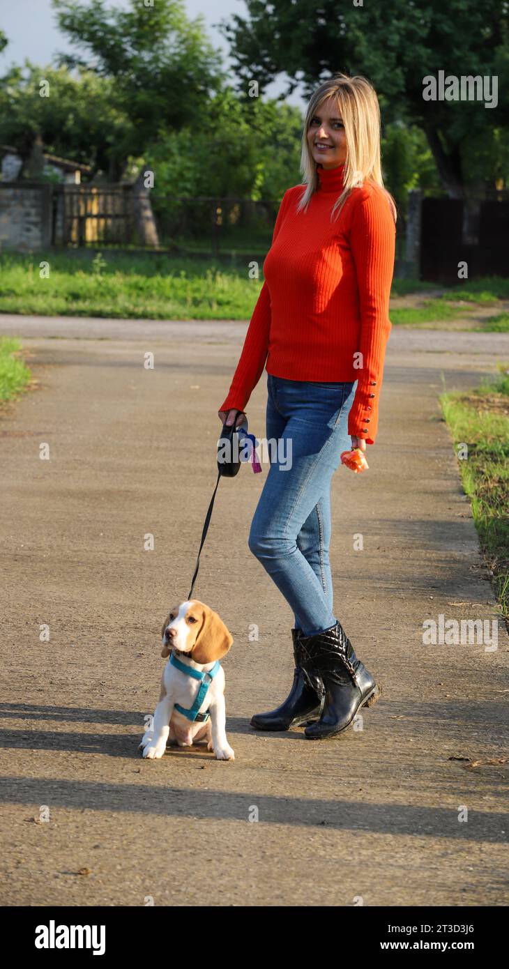 donna che cammina con il suo piccolo cane nelle giornate di sole all'aperto Foto Stock