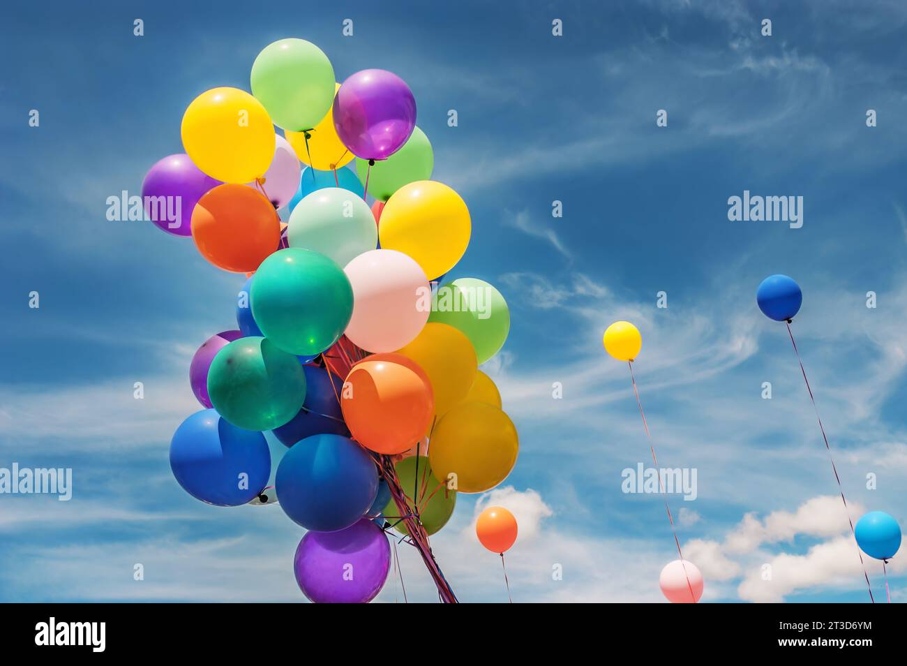 Un mazzo colorato di palloncini all'esterno contro un cielo nuvoloso Foto Stock