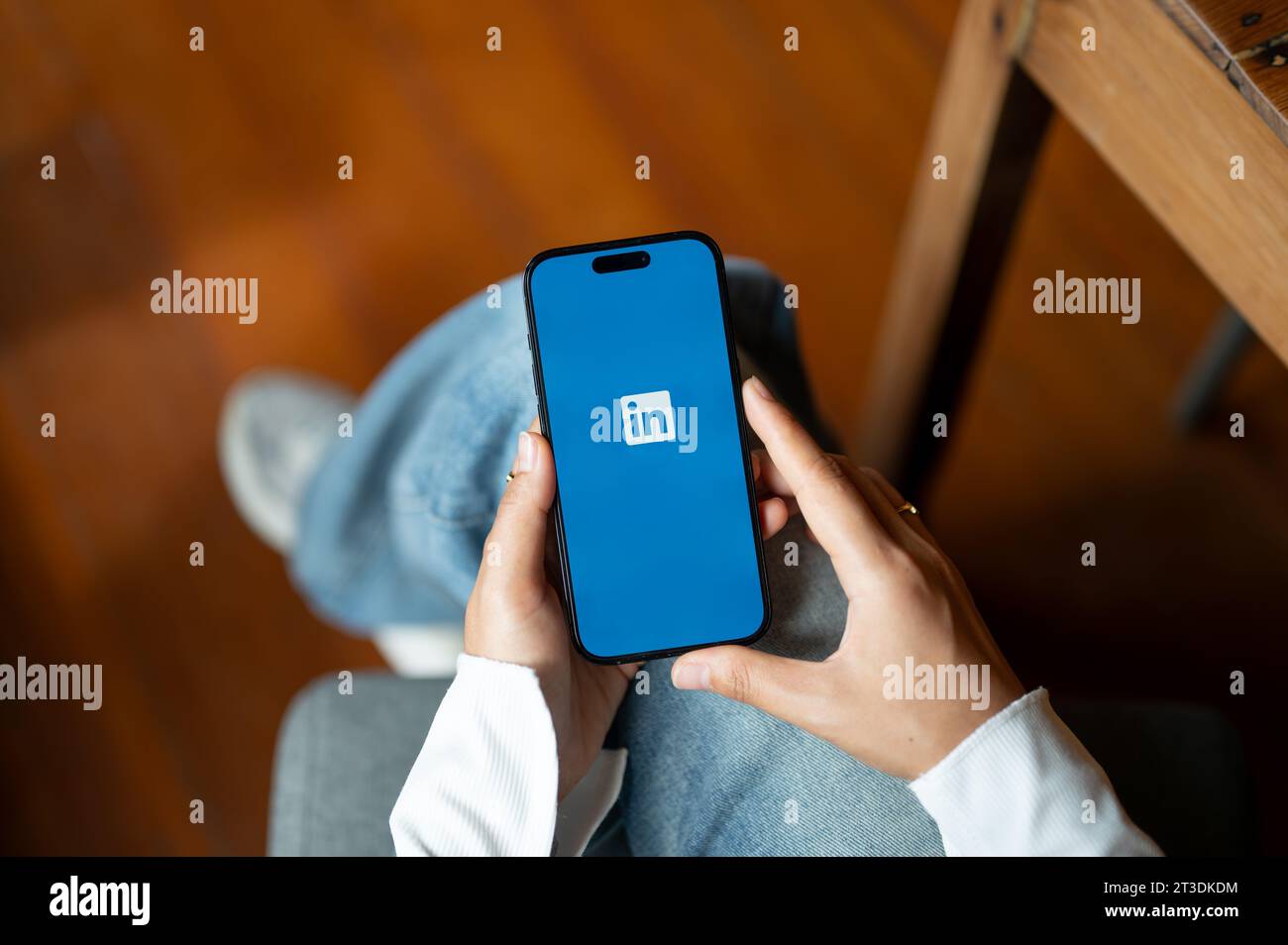 Chiang mai, Thailandia - 24 ottobre 2023: Una donna che usa LinkedIn, aggiorna il suo profilo LinkedIn sul suo Iphone14 mentre è seduta al chiuso. Logo LinkedIn su IPhO Foto Stock