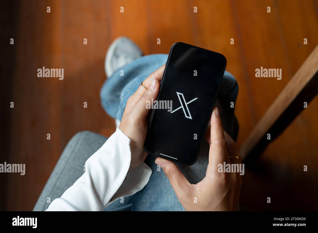 Chiang mai, Thailandia - 24 ottobre 2023: Una donna che usa X Twitter sul suo Iphone14 mentre è seduta al chiuso. X logo Twitter sullo schermo Iphone14. Piattaforma social Foto Stock