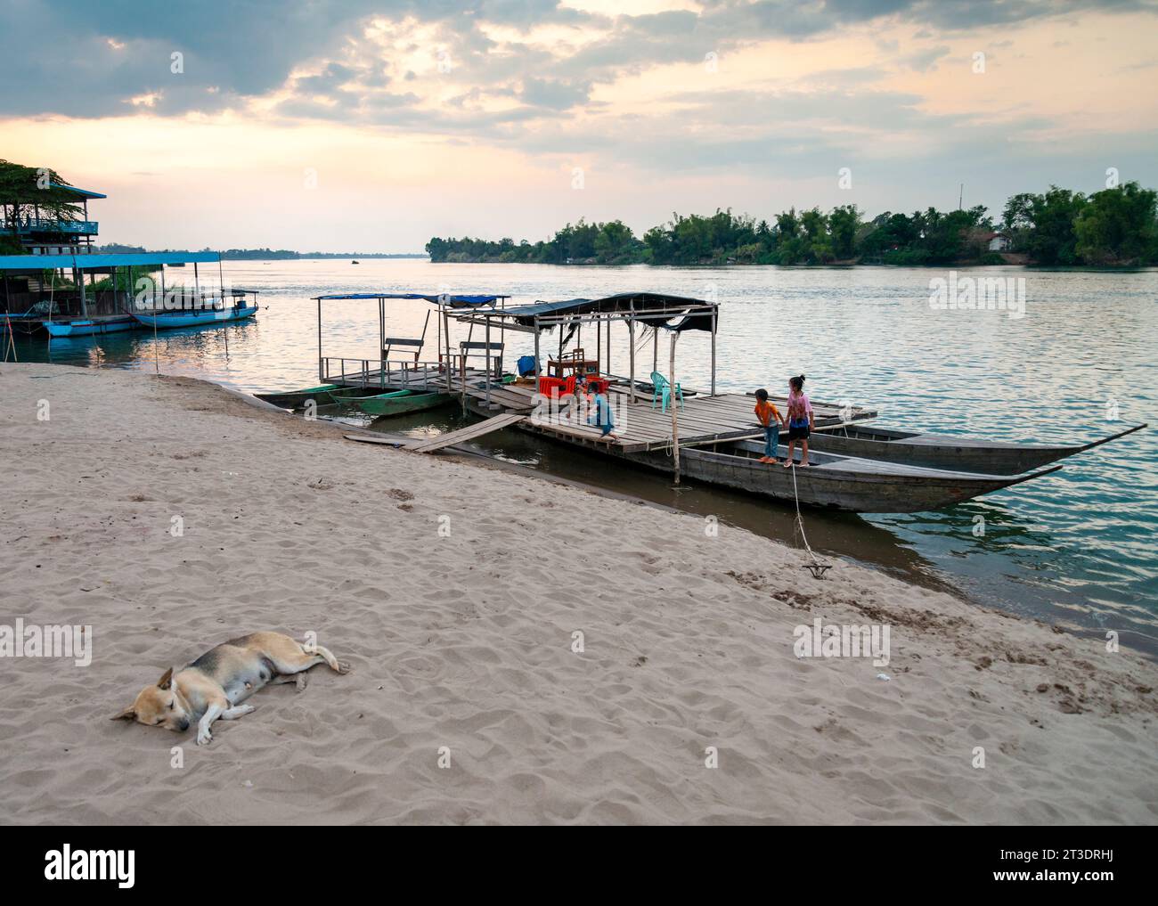 Rilassata scena del tramonto, sul fiume Mekong, piccoli viaggiatori in traghetto da e per le isole Nakasong e Don Som, qui al molo della spiaggia sabbiosa, principale Foto Stock