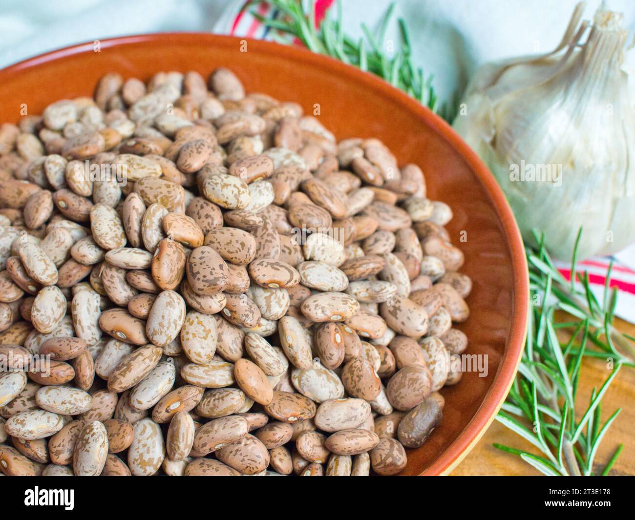 Immagine ravvicinata di STILL Life di legumi di fagioli di pinto con rametto di rosmarino e aglio per una dieta vegetariana sana e ispirata. Foto Stock