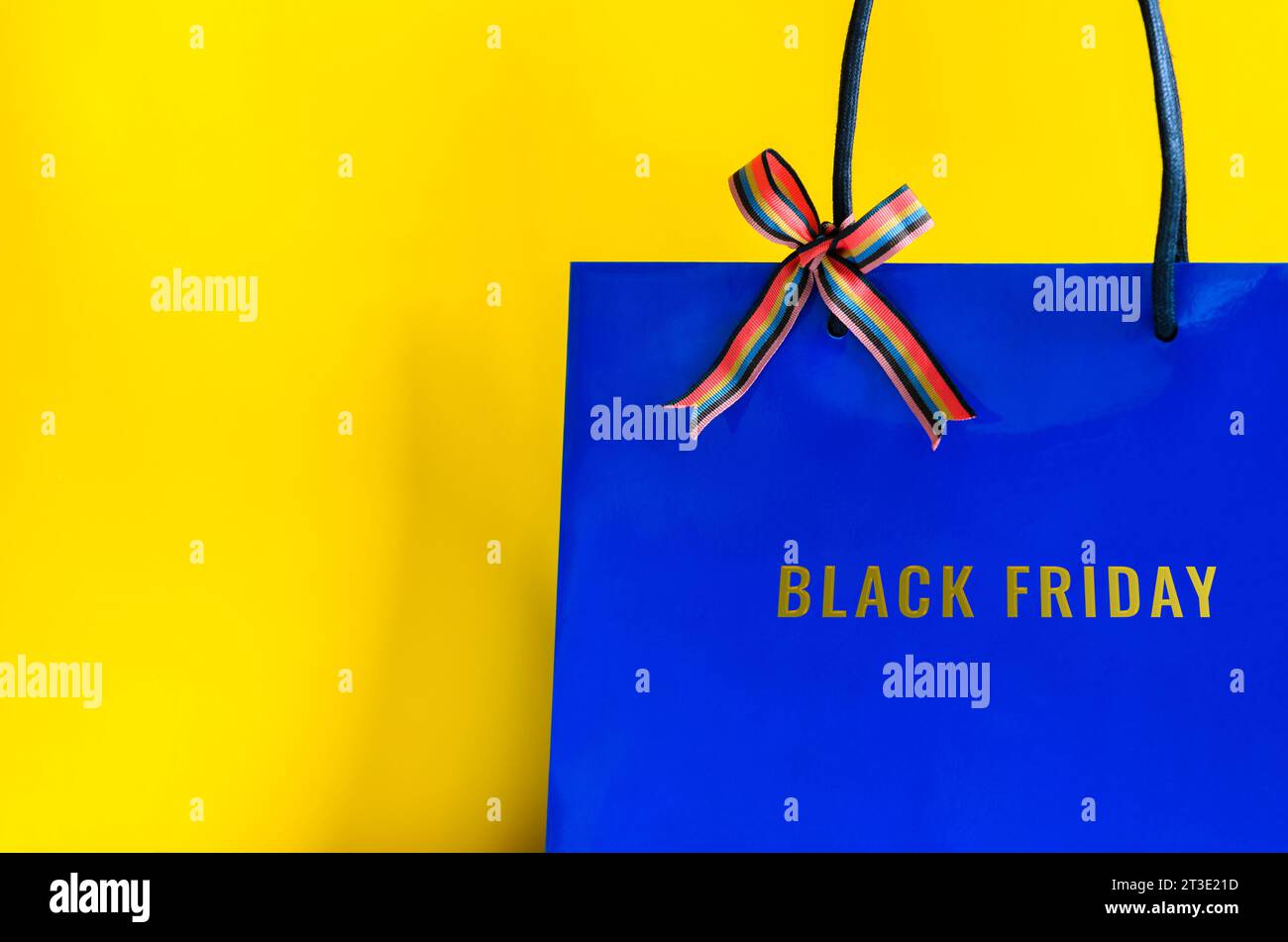 Shopping bag blu con nastro e parola del Black Friday su sfondo giallo per il concetto di shopping del Black Friday. Foto Stock