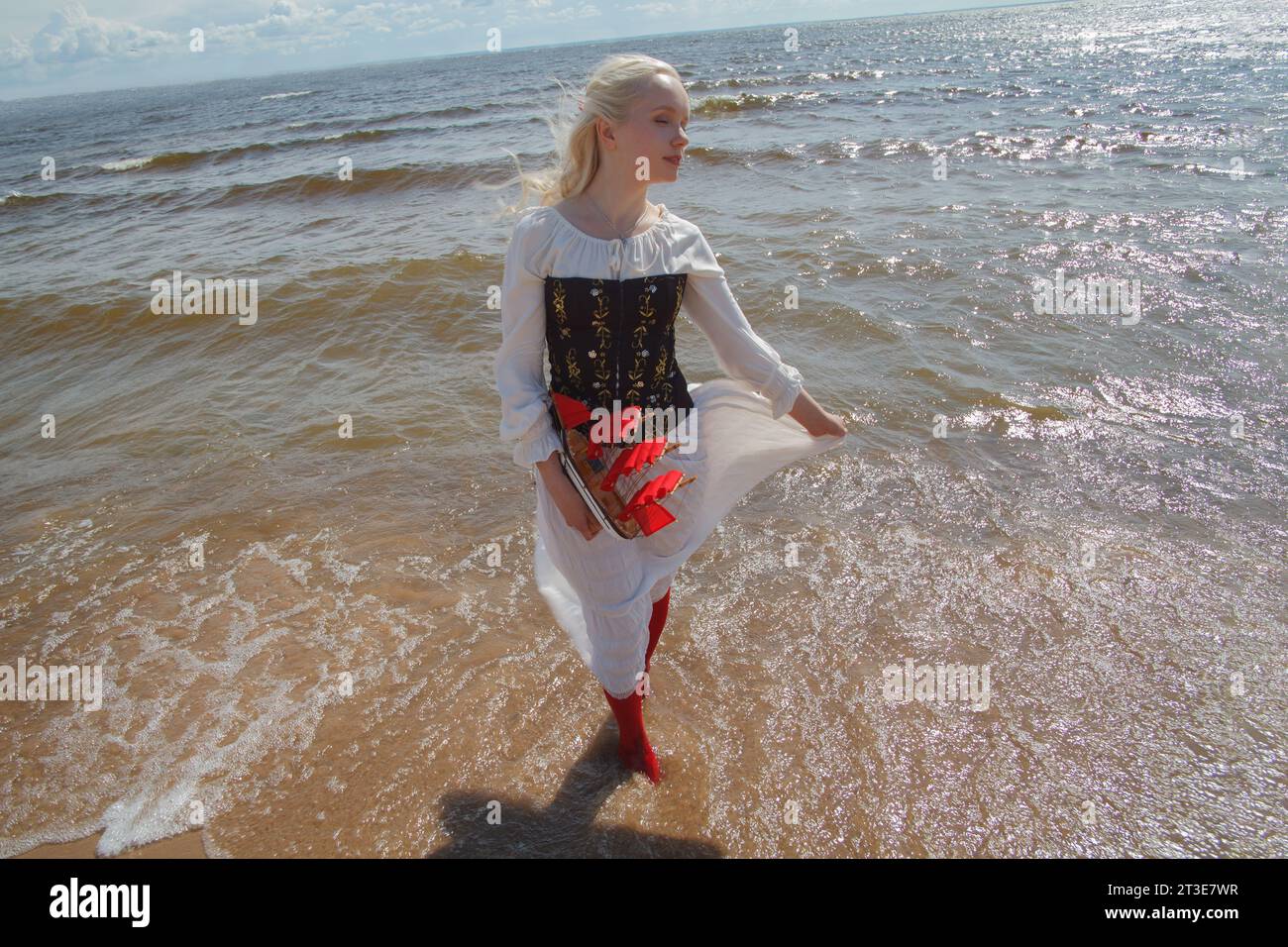 Giovane donna che cammina lungo la costa, posa in abito vintage Foto Stock