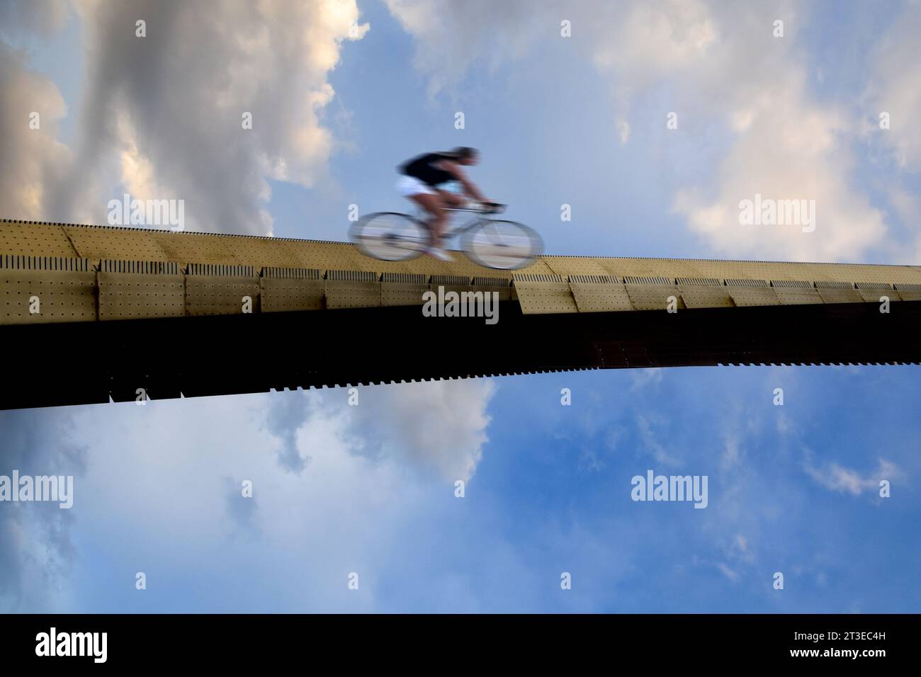 Ciclista che attraversa un ponte, sfondo del cielo. Foto Stock