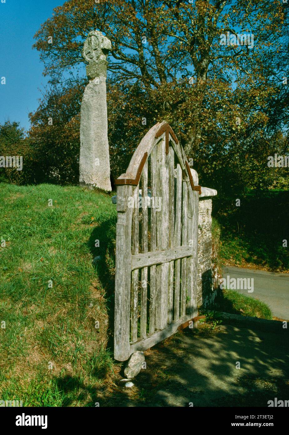 Un pilastro di granito inciso C6th sormontato da una croce medievale rieretta accanto al cancello del sagrato di Cardinham, Cornovaglia, Inghilterra, Regno Unito. Foto Stock
