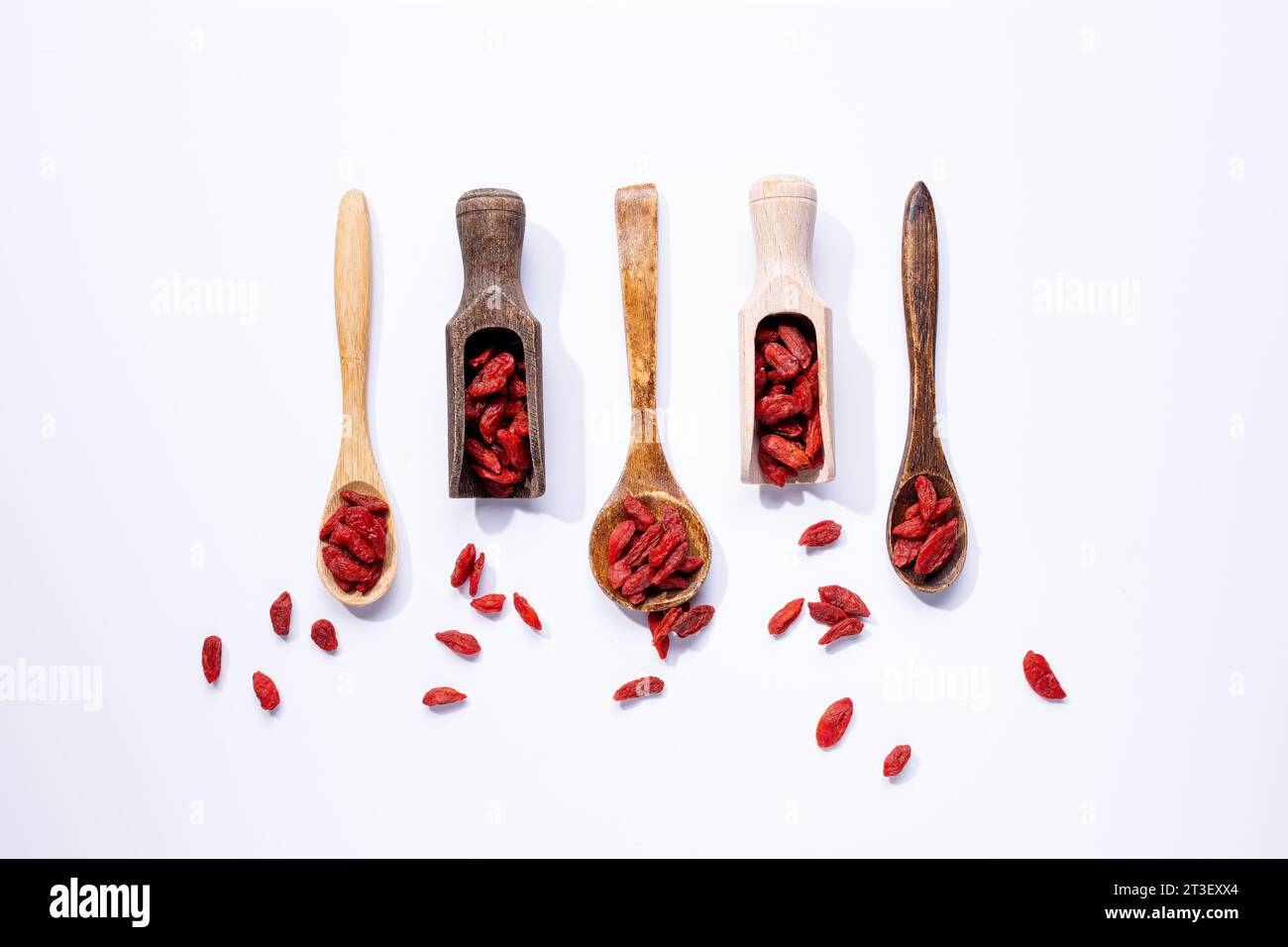 Bacche di goji essiccate su cucchiai di legno isolati su sfondo bianco. Foto Stock