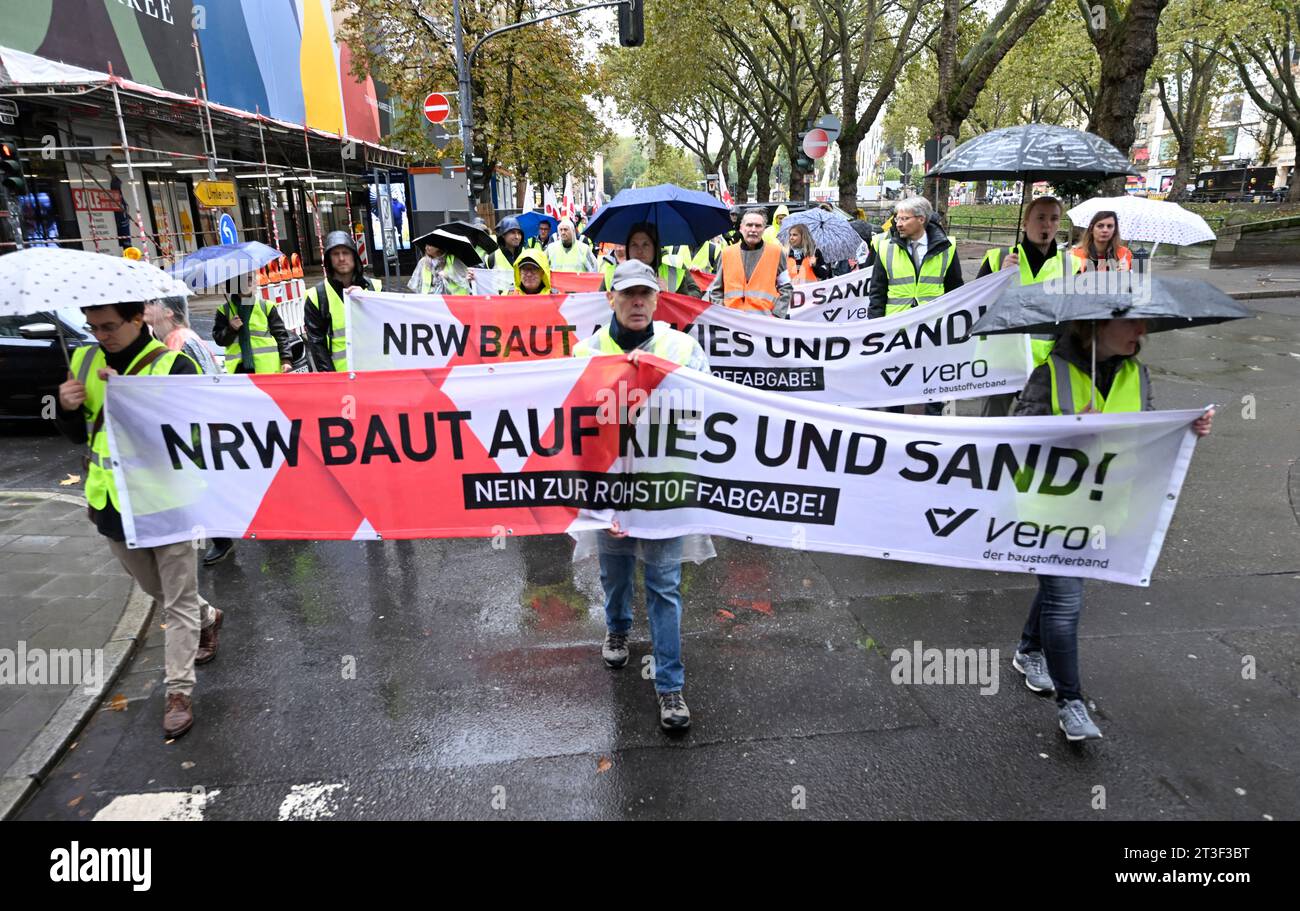 Duesseldorf, Germania. 25 ottobre 2023. I lavoratori industriali manifestano davanti al parlamento statale contro la prevista tassa sulle materie prime, tenendo uno striscione con la scritta "l'NRW si costruisce su ghiaia e sabbia”. La manifestazione è stata organizzata dall'associazione dei materiali da costruzione vero per protestare contro la tassa sulle materie prime prevista per il 2024. Crediti: Roberto Pfeil/dpa/Alamy Live News Foto Stock