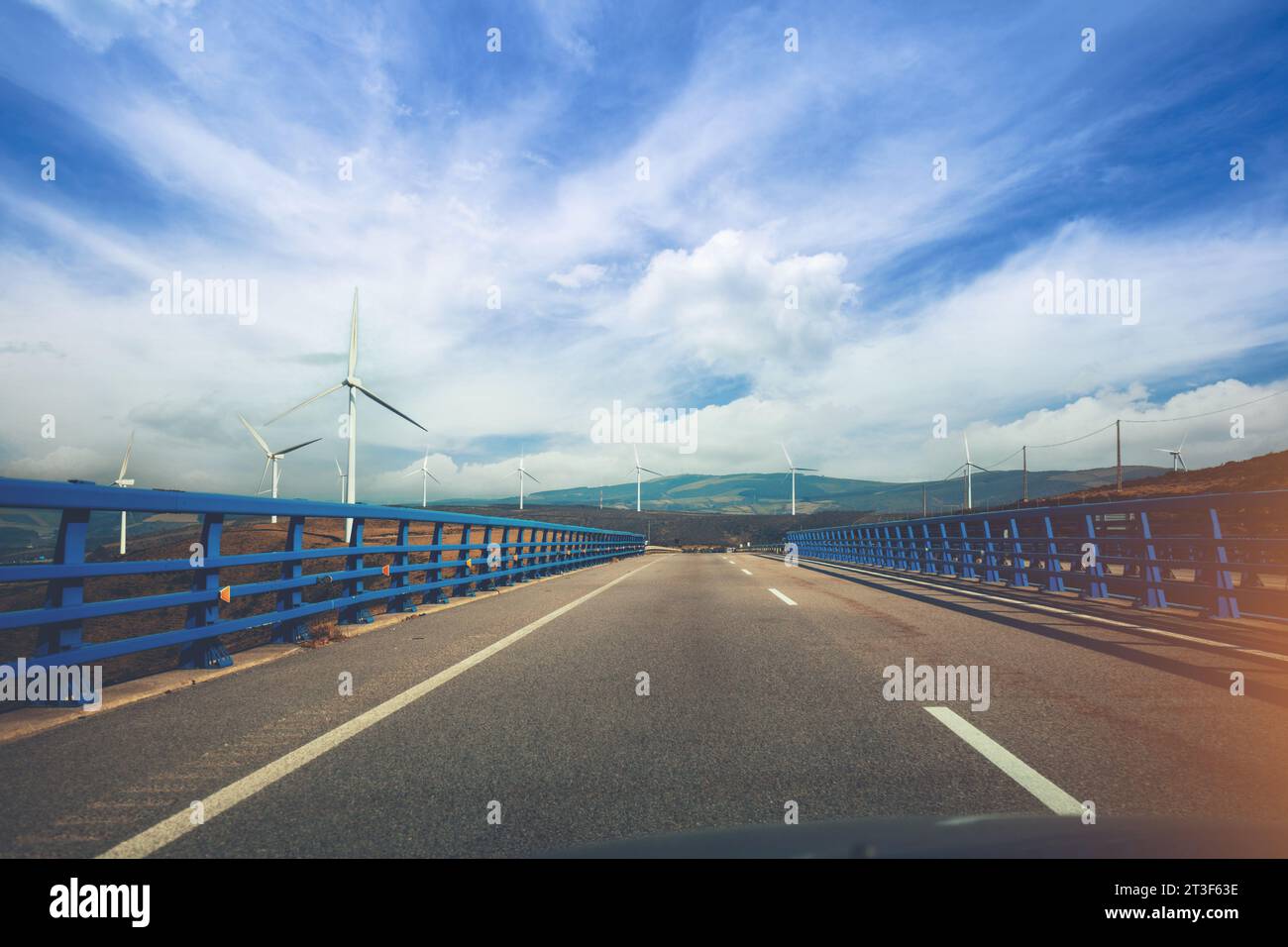 Vista del ponte sul fiume attraverso il parabrezza. Bellissimo paesaggio con autostrade, ponti e generatori di vento. Asturie, Spagna Foto Stock