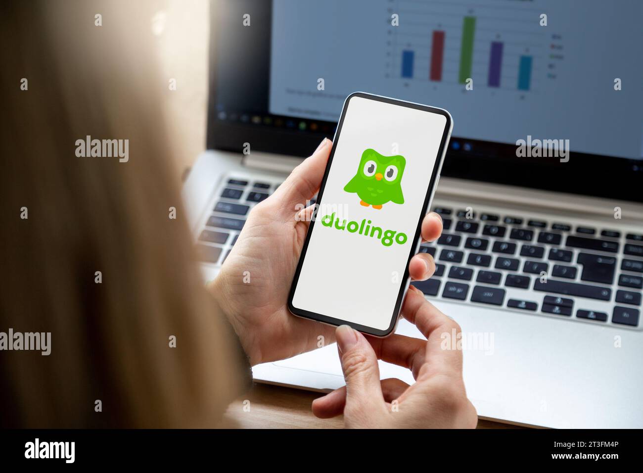 Donna d'affari nel suo ufficio che possiede uno smartphone con l'app per l'apprendimento delle lingue Duolingo sullo schermo. Rosario, Argentina - 20 ottobre 2023. Foto Stock