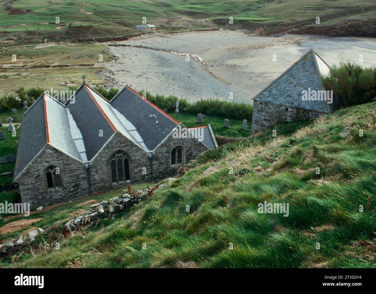 Chiesa e torre W indipendente di St Winwaloe Looking se a Church Cove, Gunwalloe, Cornovaglia, Inghilterra, Regno Unito. Il campanile costruito nella scogliera è C13th. Foto Stock