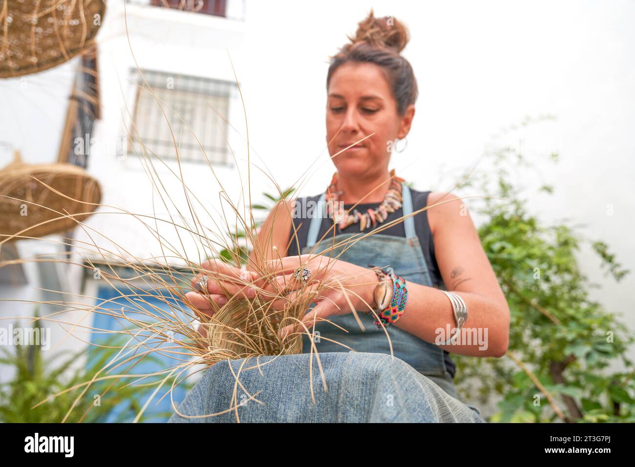 Vista frontale di una donna ispanica che tesse un cesto con fibre di sparto. Lavoro manuale, tradizione e cultura. Foto Stock