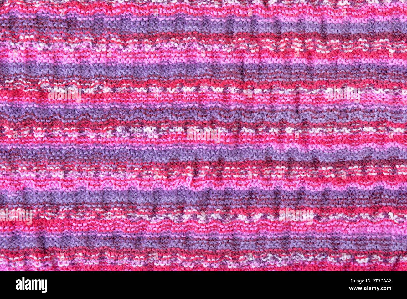 Sfondo colorato a maglia astratta. Motivo ondulato di fili di maglia rosa, blu, giallo e viola. Primo piano di una coperta a maglia. Copia spazio Foto Stock