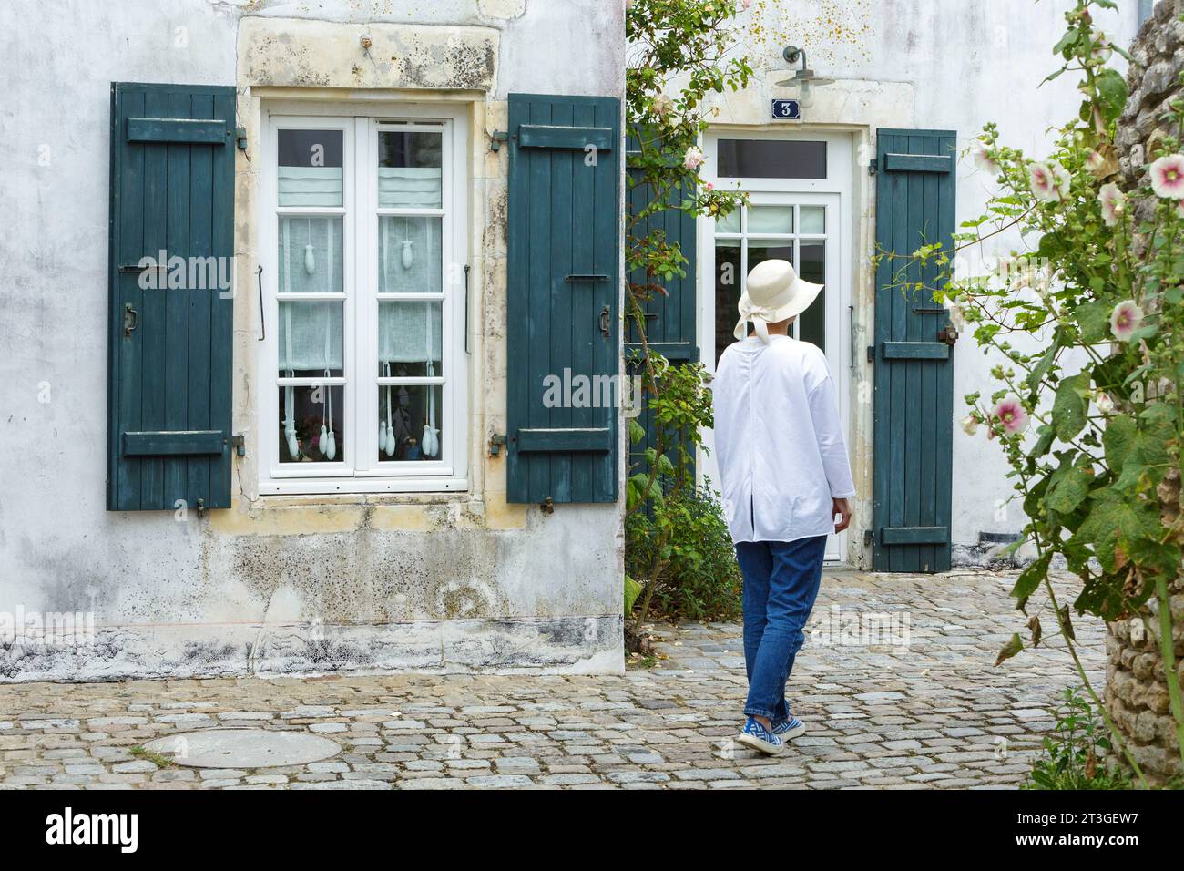 Francia, Charente Maritime, Ile de Re, Woma che passeggia accanto a una casa Foto Stock