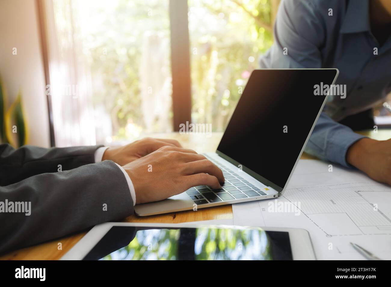 Uomo d'affari che lavora in ufficio con notebook e Blueprint. Architetto discutere con ingegnere circa il progetto in ufficio. Foto Stock
