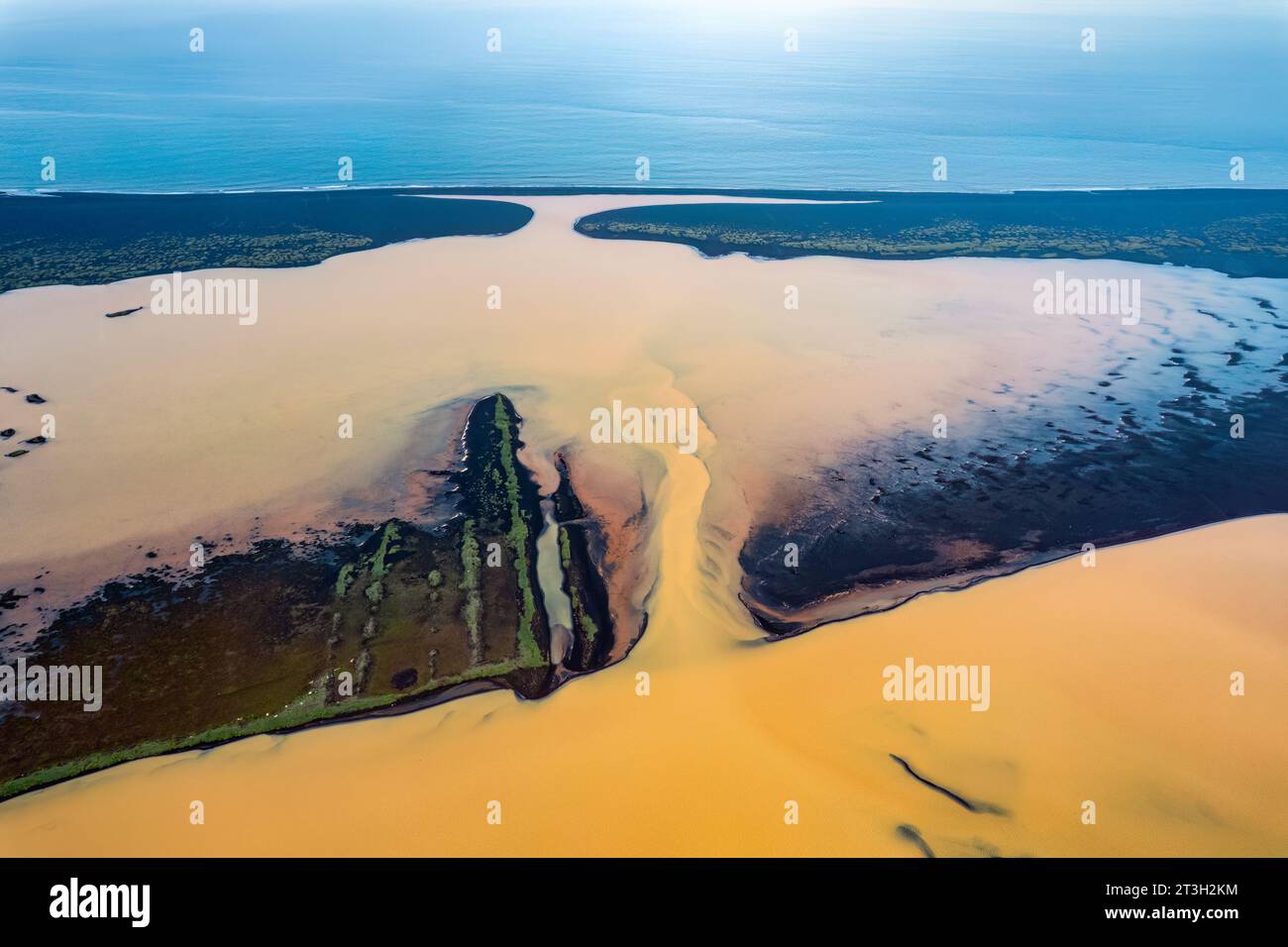 Vista aerea dei sedimenti ricchi di zolfo affluenti del fiume giallo dall'area vulcanica che si scioglie e scorre attraverso la spiaggia di sabbia nera fino all'oceano in natura Foto Stock