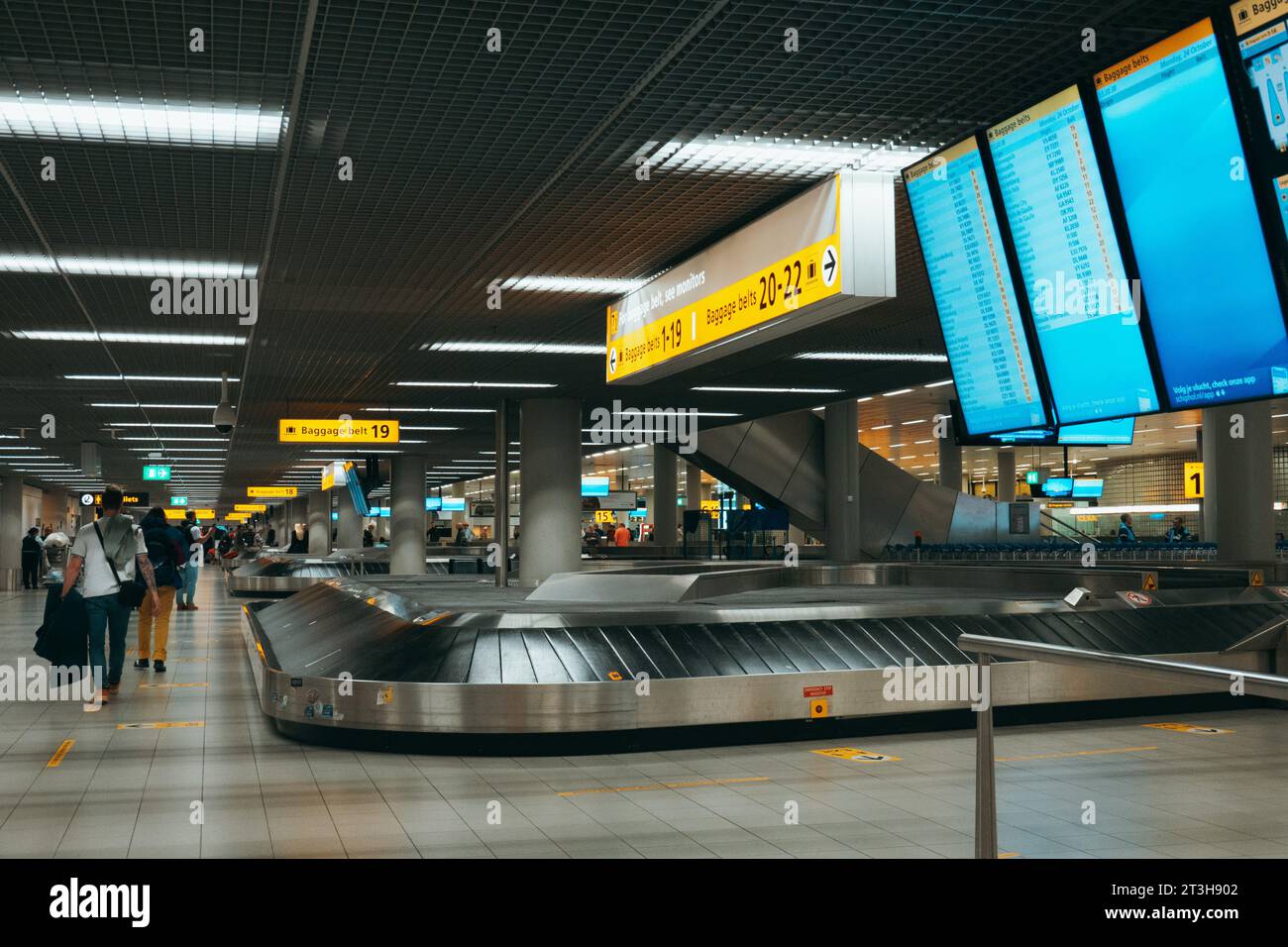 Caroselli bagagli nella sala di ritiro bagagli degli arrivi dell'aeroporto Schiphol di Amsterdam Foto Stock