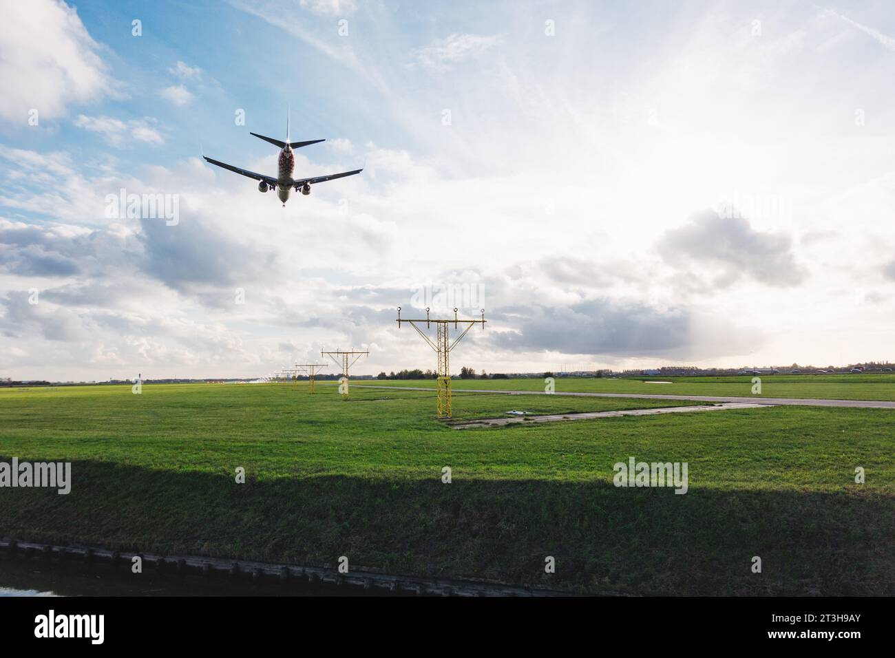 Un Boeing 737 vola sopra le luci di avvicinamento atterrando sulla pista Polderbaan dell'aeroporto Schiphol di Amsterdam in un soleggiato pomeriggio autunnale Foto Stock