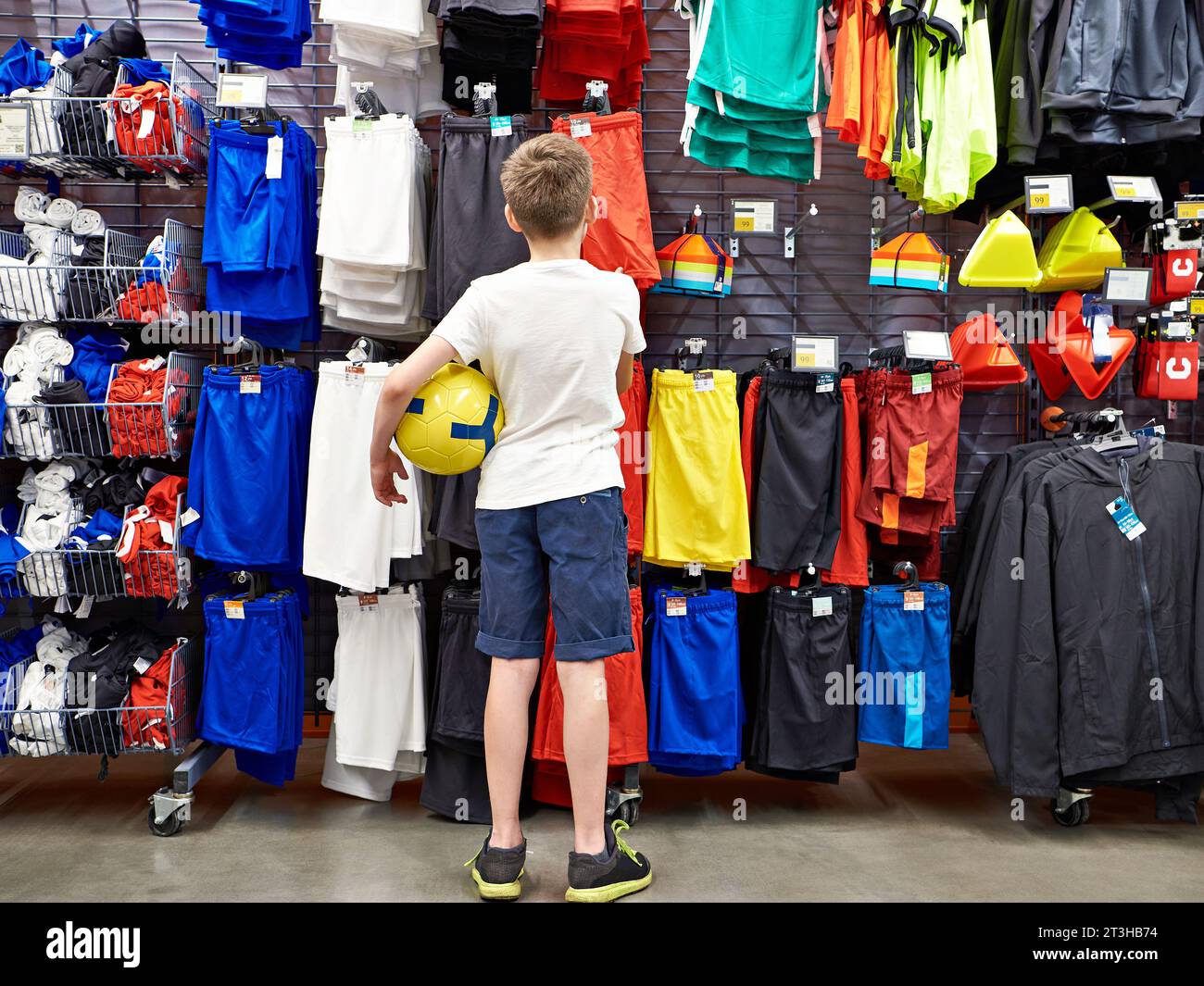 Ragazzo con una palla in un negozio di abbigliamento da calcio Foto Stock