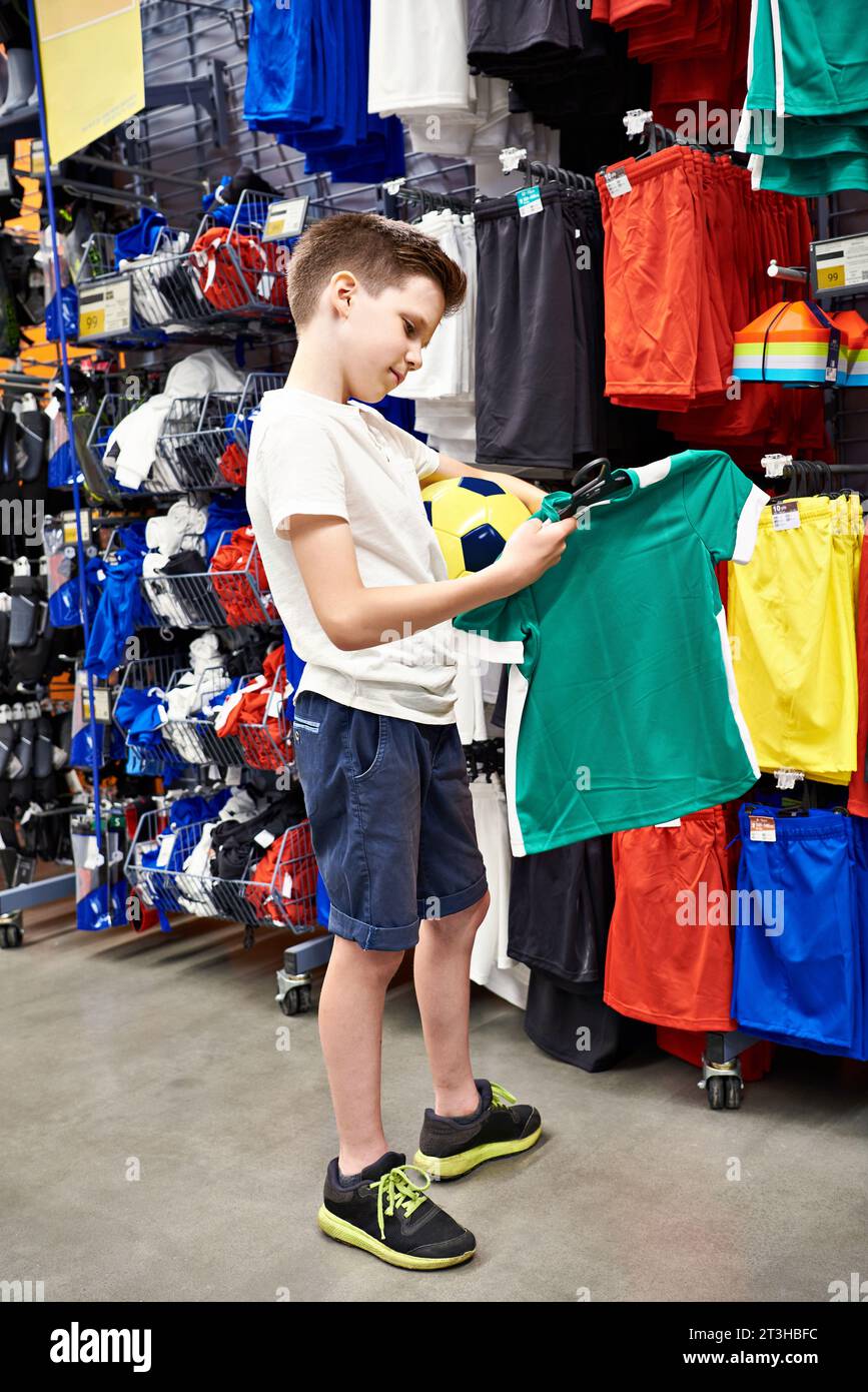 Ragazzo con una palla in un negozio di abbigliamento da calcio Foto Stock