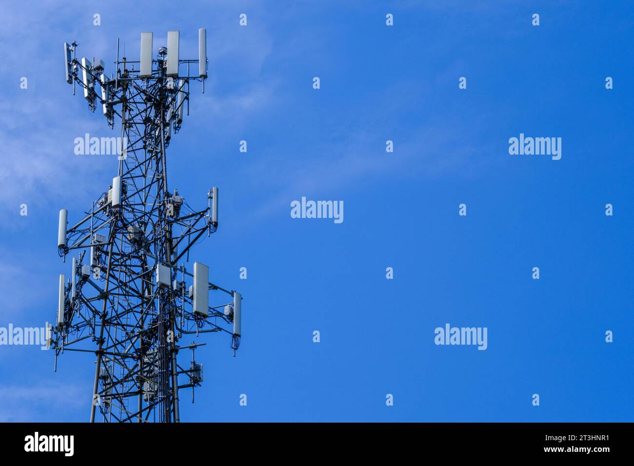 Una fotografia della parte superiore di una torre dell'antenna cellulare contro un cielo blu con spazio per la copia. Foto Stock